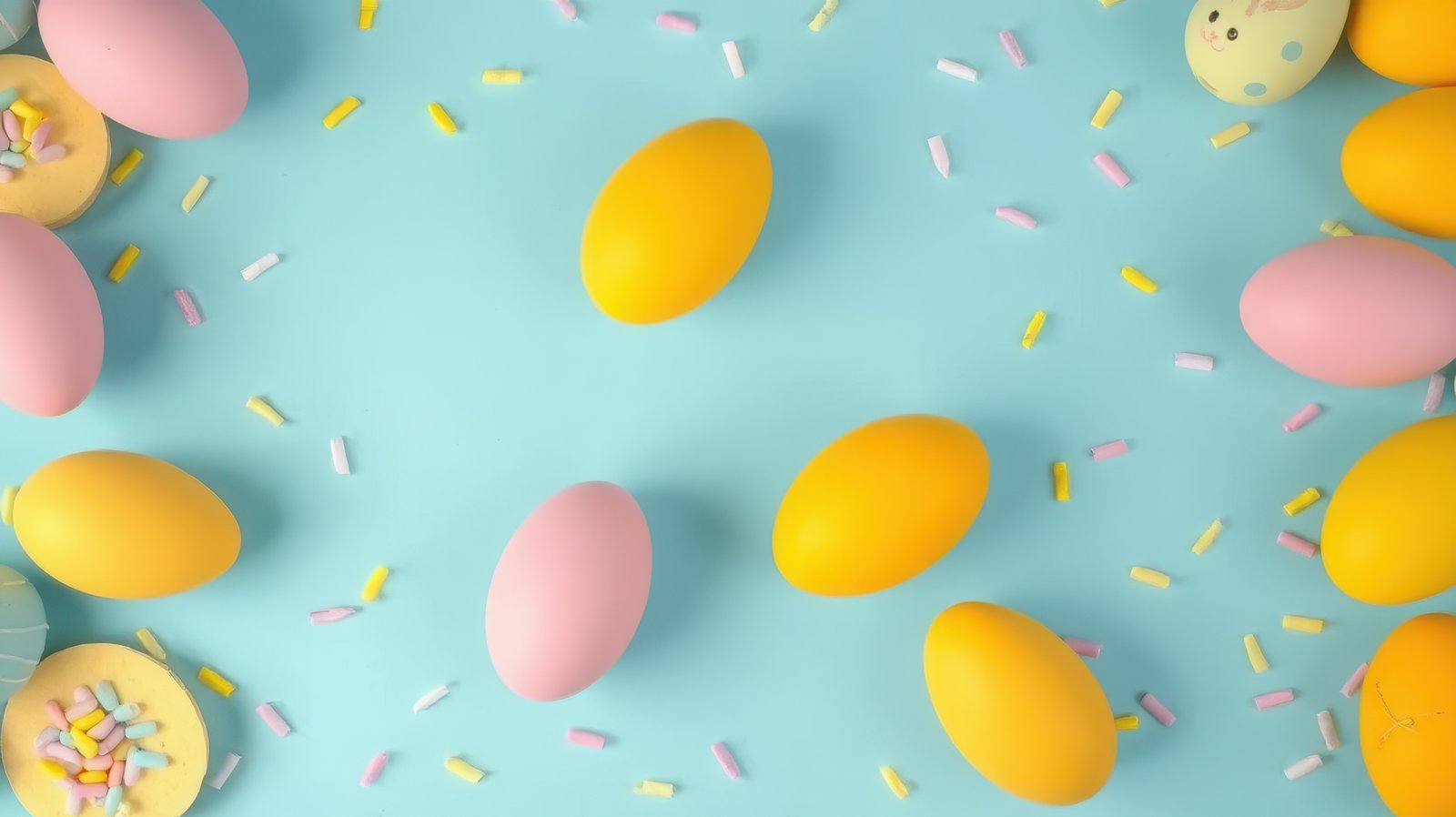 Colorful Easter eggs arranged on a blue background with sprinkles creating a festive atmosphere for spring celebrations